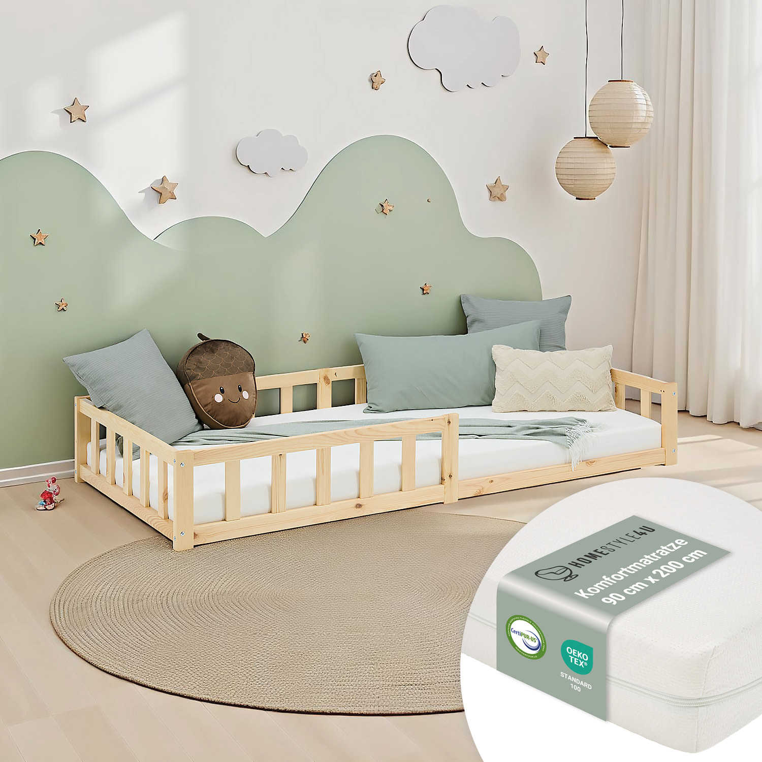 Kinderbett in Naturholzfarbe mit Elementen aus Kiefernholz, Lattenrost, Matratze und seitlichen Schutzgittern. Das niedrige Kinderbett ist mit Matratze und mehreren Kissen vor weißem Hintergrund abgebildet. Seitliche Schutzleisten und ein niedriger Einsti