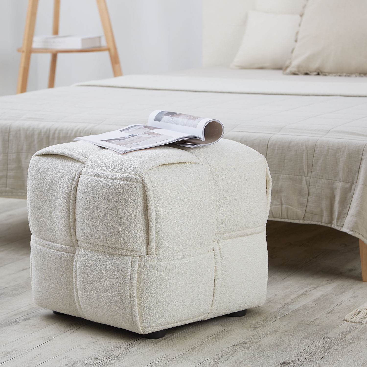 Sitzhocker in Beige mit Bouclé-Bezug. Der Artikel ist freigestellt auf weißem Hintergrund abgebildet. Sichtbare Details sind ein regelmäßig gesteppter Bezug und eine abgerundete Würfelform.
