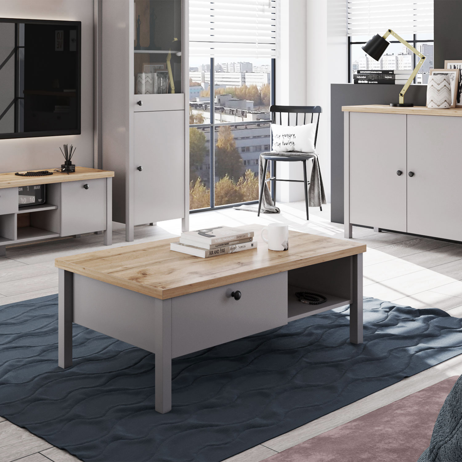 Couchtisch in Grau mit Holzelementen, Schubladenstauraum und Stauraum. Der Artikel ist freigestellt auf weißem Hintergrund abgebildet. Sichtbare Details sind eine rechteckige Tischplatte, Schubladenfronten, offene Ablagen und eine naturfarbene obere Holzp