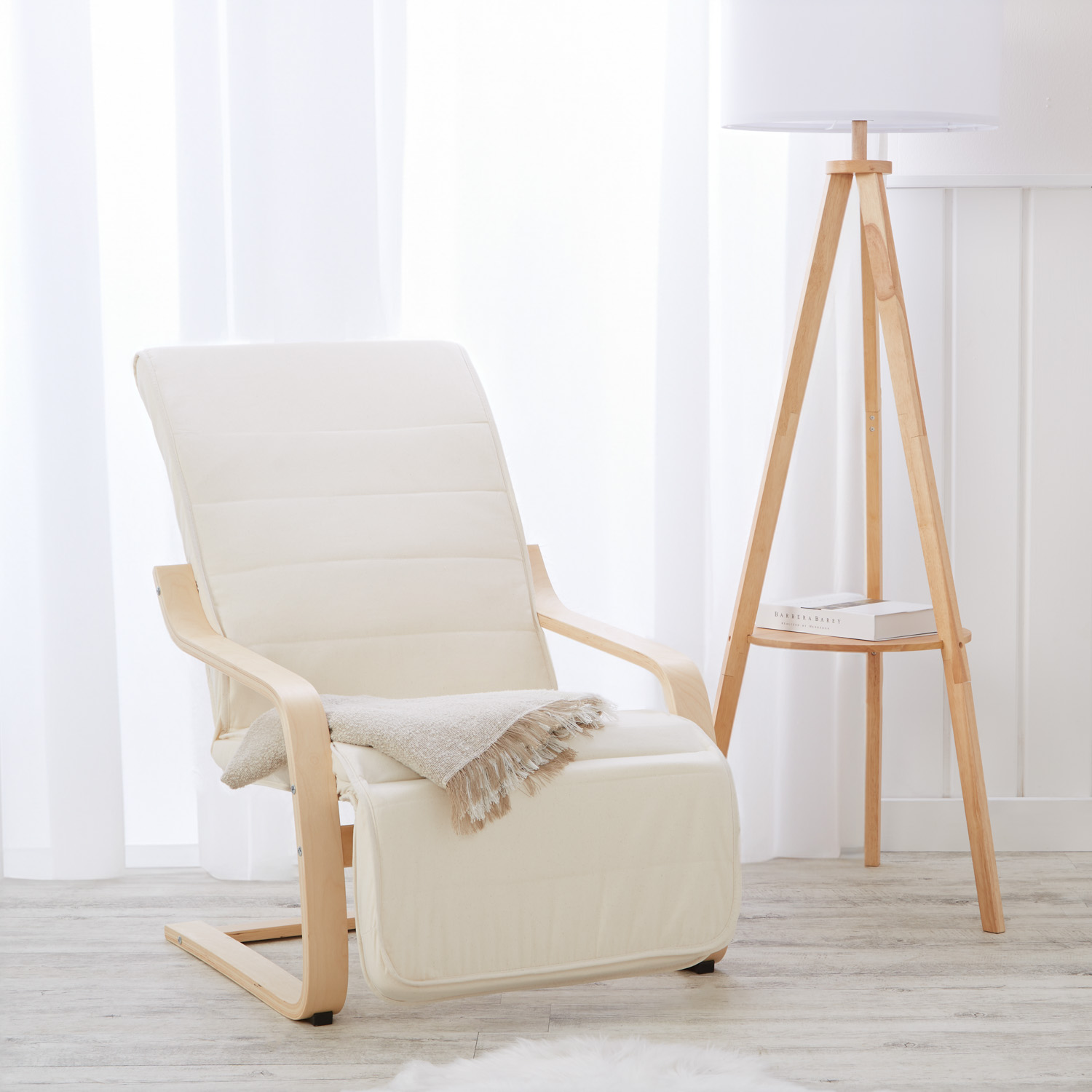Relaxsessel in Naturholzfarbe mit Holzelementen. Der gepolsterte Sessel mit gebogenen Holzarmlehnen und ausgezogenem gepolstertem Fußbereich ist einzeln vor weißem Hintergrund abgebildet. Kopfpolster, waagerechte Ziernähte und das geschwungene Holzunterge
