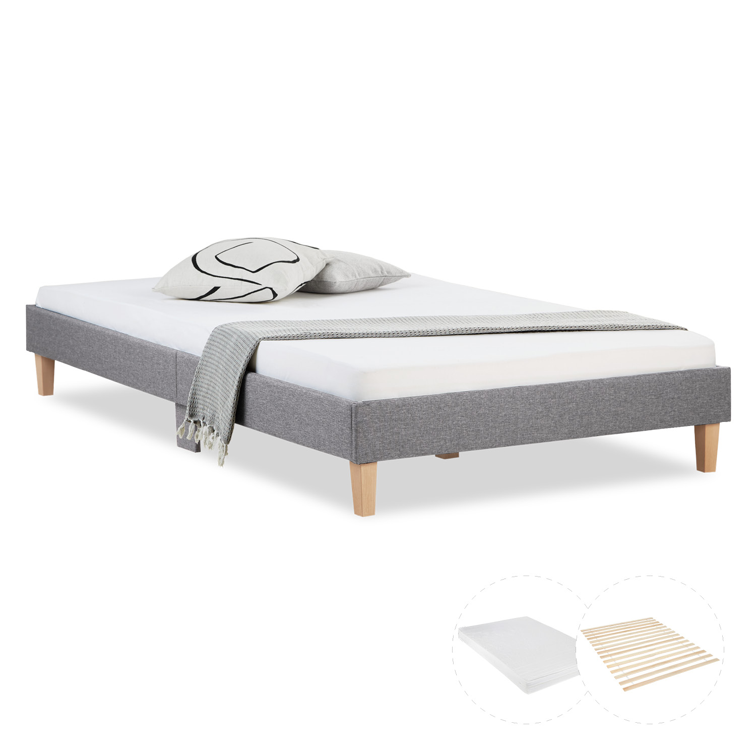 Polsterbett in Grau mit Stoffbezug, Lattenrost und Matratze. Das niedrige Polsterbett ohne Kopfteil ist mit Matratze, Bettwäsche und Kissen auf weißem Hintergrund abgebildet. Der dunkle Rahmen und die kurzen Holzbeine sind sichtbar.