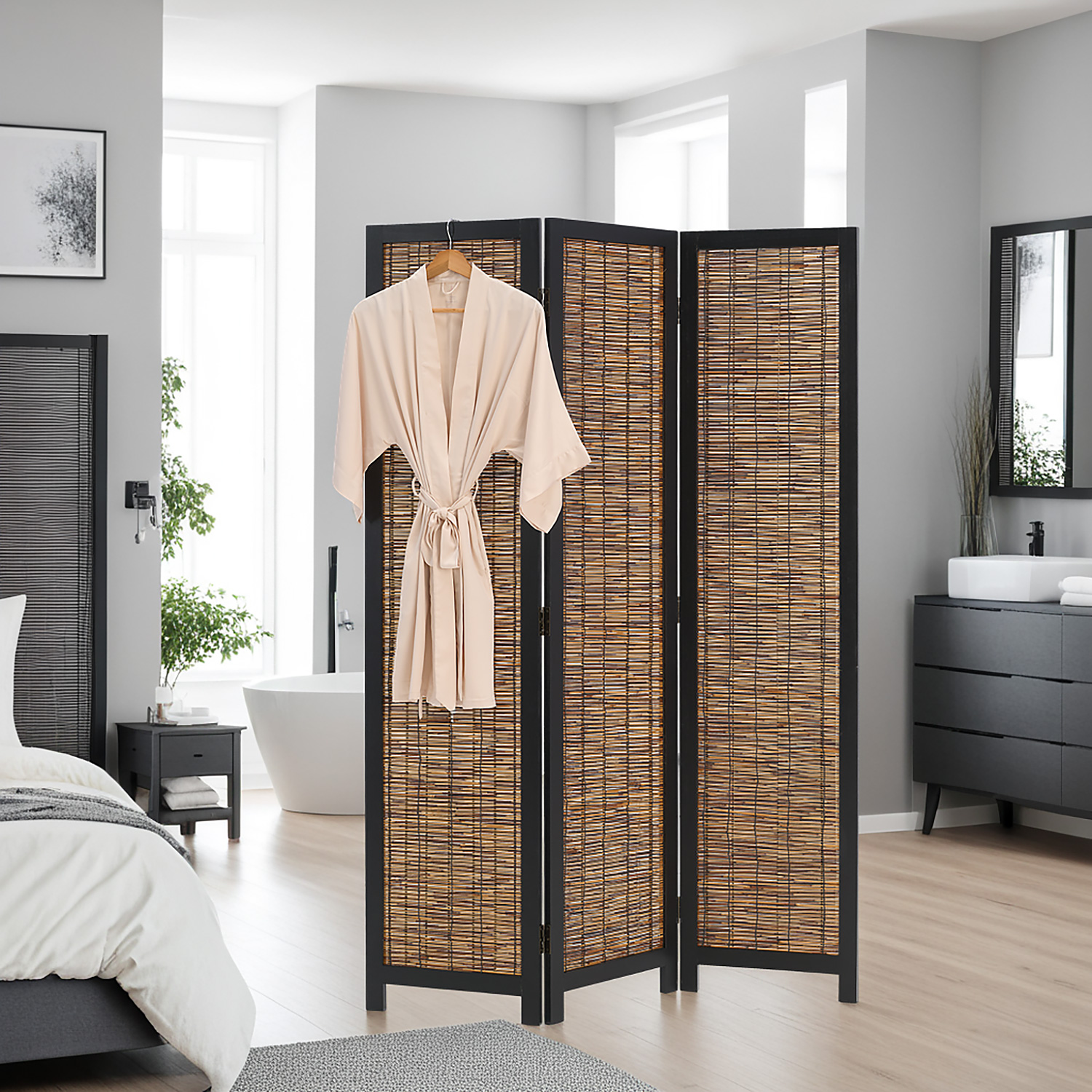 Paravent in Schwarz mit Holzelementen, 3 beweglichen Elementen und Weidenelementen. Der aufgefaltete Paravent mit schwarzem Rahmen und naturfarbenen Flechtflächen steht vor weißem Hintergrund. Ein heller Bademantel hängt über dem linken Element.