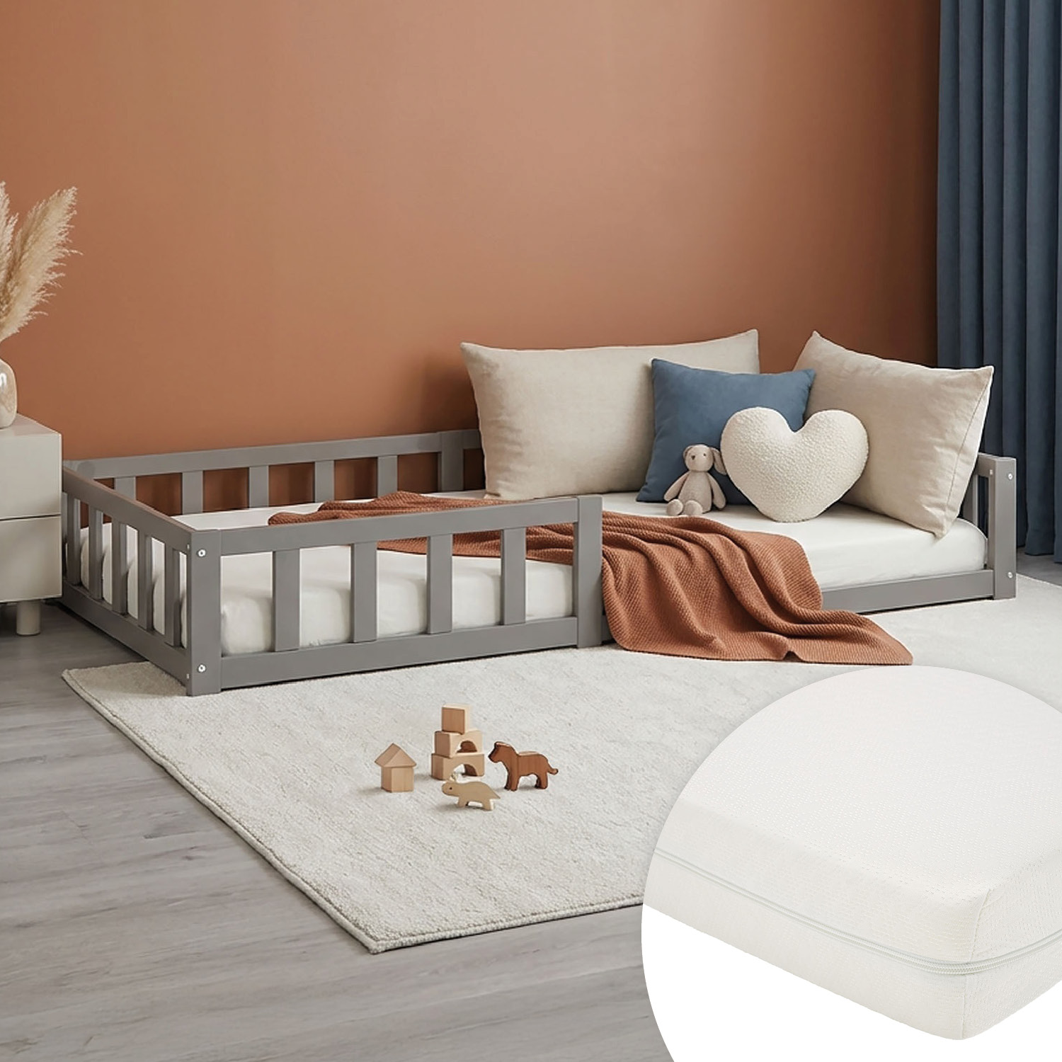 Kinderbett in Grau mit Elementen aus Kiefernholz, Matratze und seitlichen Schutzgittern. Das Bett ist mit Matratze, Bettwäsche und mehreren Kissen vor weißem Hintergrund abgebildet. Der Rahmen und die kurze Unterkonstruktion sind sichtbar.